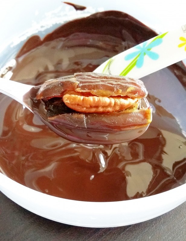 Nosta pähkinällä täytetty taateli sulan suklaan päälle lusikkaan.